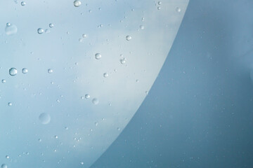 A macro image of suspended oil bubbles forming an abstract pattern in clear liquid. The smooth,...