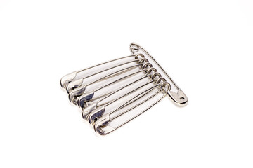 A metallic safety pin brooch composed of multiple pins secured to a single clasp, isolated on a...