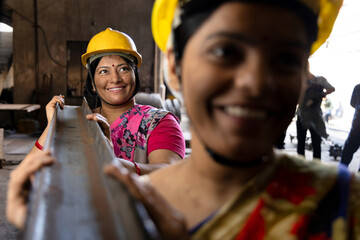 Female iron Factory Worker at work moving iron poles.