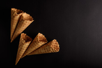 Four waffle cones displayed on a dark backdrop highlight their texture and design, perfect for...