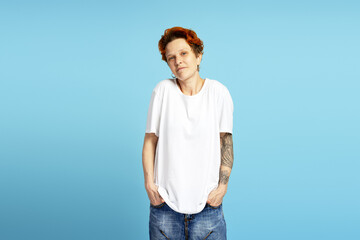 Confused young woman with piercing shrugging, looking at camera over blue background