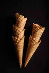 Five waffle cones stacked perfectly against a dark backdrop, ideal for serving a variety of ice...