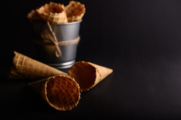 Waffle cones are arranged in a metal bucket with several empty cones laid out, ready for delicious...
