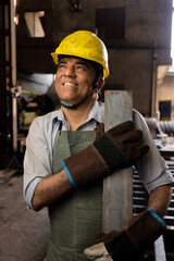 Indian Mechanical Engineer wearing safety yellow hard hat smiling while standing cross arm. Industrial factory worker concept.