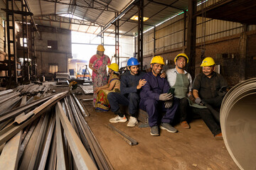 Fototapeta premium Team of indian engineers wearing safety hard hat and having a fun together at industrial factory taking break from work, skill india concept.