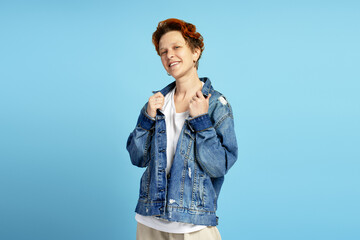 Happy young woman with short red hair and piercings on blue background