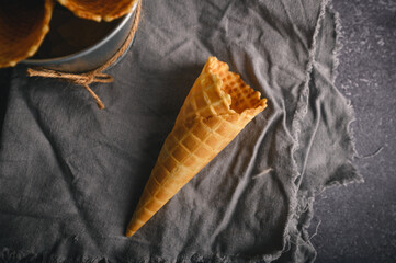 Waffle cone sits on a textured cloth, waiting to be filled with creamy ice cream, perfect for a...