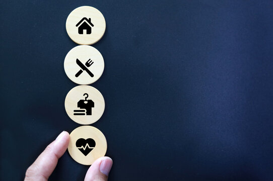 wooden cube with icons of food, Clothing, housing, medical bag, four basic human needs concepts. The Four Basic Material Needs of the Human Being