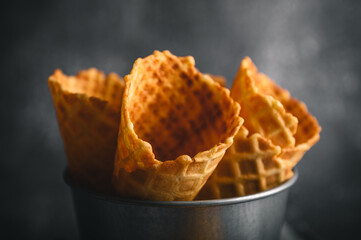Several waffle cones are arranged in a metal bucket, showcasing their golden-brown texture and...