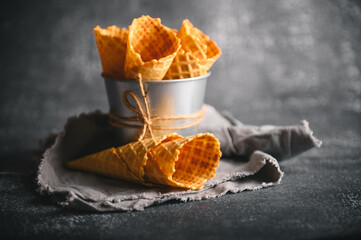 Waffle cones are arranged in a metal cup on a rustic table, ready to be filled with delicious ice...