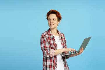Portrait of tattooed woman with facial and ear piercings, holding laptop in studio