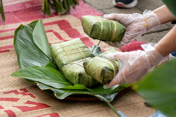 Woman with traditional Tay dress Making (wrapping) Tet Cake, the Vietnamese lunar new year Tet food...