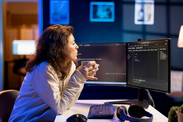 Programmer drinking cup of coffee in the morning, securing company servers from virus attacks. IT...