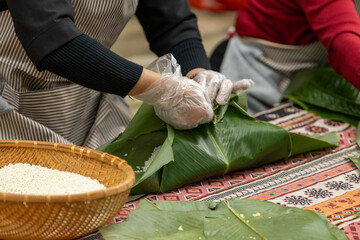Woman with traditional Tay dress Making (wrapping) Tet Cake, the Vietnamese lunar new year Tet food...