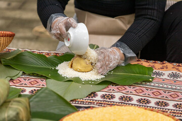 Woman with traditional Tay dress Making (wrapping) Tet Cake, the Vietnamese lunar new year Tet food...