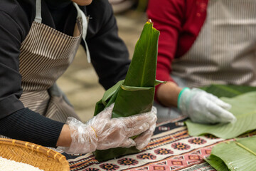 Woman with traditional Tay dress Making (wrapping) Tet Cake, the Vietnamese lunar new year Tet food...