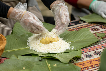 Woman with traditional Tay dress Making (wrapping) Tet Cake, the Vietnamese lunar new year Tet food...
