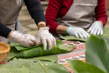Woman with traditional Tay dress Making (wrapping) Tet Cake, the Vietnamese lunar new year Tet food...