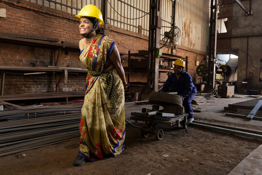 Woman moves an empty pallet jack through an industrial hall.