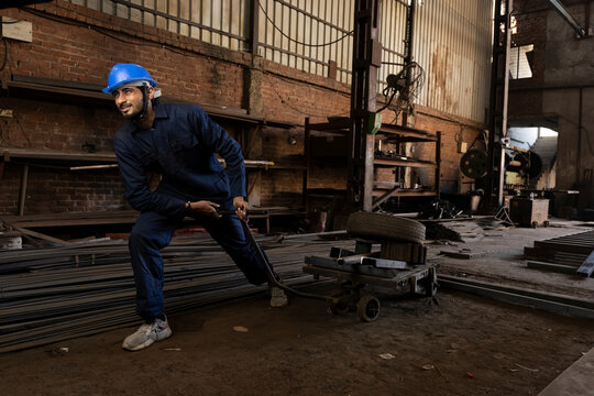 Factory worker with cage trolley at factory