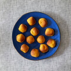 Freshly air - fried pumpkin dough balls, neatly arranged on a blue plate, await tasting. Their golden - brown, slightly crispy exteriors and soft interiors make for a tempting homemade treat.