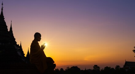 Fototapeta premium silhouette of buddhist monks praying in front of temple at sunset