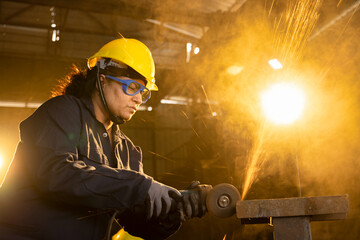 Side view portrait of mature female worker cutting metal at industrial plant