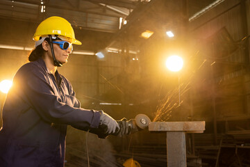 Side view portrait of mature female worker cutting metal at industrial plant.