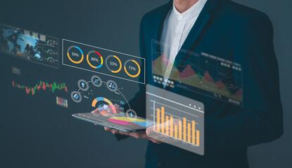A business professional interacts with a tablet displaying futuristic digital charts and graphs...