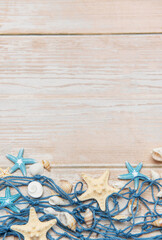 Fishing net with starfishes and seashells creating summer holiday border on wooden planks