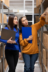 Female workers team in a local business depot preparing packages for express delivery. Packed boxes...