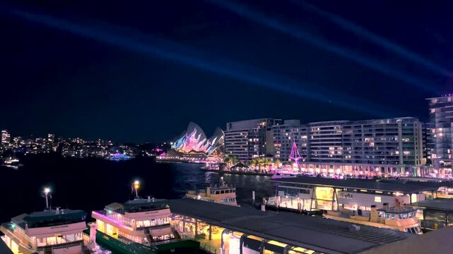 Sydney, Australia -June 11, 2025: 4k Video -Sydney Harbour illuminated for the annual Vivid Festival of lights at East Circular Quay -Panning view from above with Harbour Bridge and Opera House.