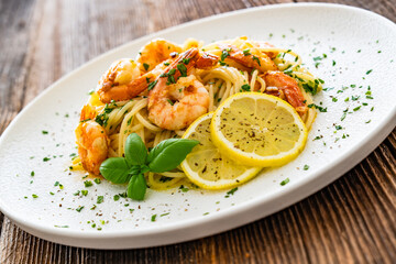 Spaghetti with fried shrimps, olive oil and parsley on wooden table
