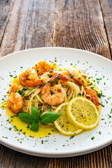 Spaghetti with fried shrimps, olive oil and parsley on wooden table
