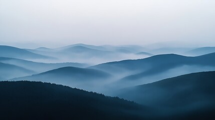 Fototapeta premium Serene misty mountain landscape, showcasing rolling hills shrouded in a bluish haze, creating a tranquil and ethereal atmosphere