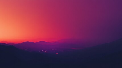Vibrant sunset over a hazy mountain range, with city lights faintly visible in the valley below. The image is slightly blurred, creating a dreamy atmosphere