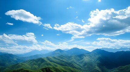 Fototapeta premium Panoramic view of lush green mountains under a vibrant blue sky, dotted with fluffy white clouds. A picturesque landscape scene