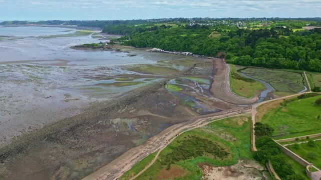 Distant drone view of the lush coastline with muddy tidal zone on greenery environment, Paimpol, Brittany, France.