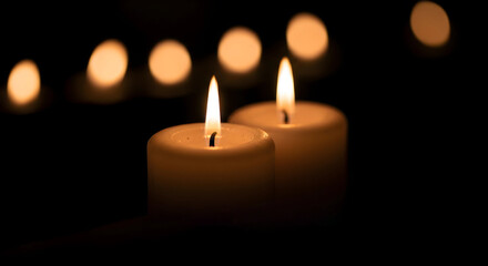 Two burning candles on dark background