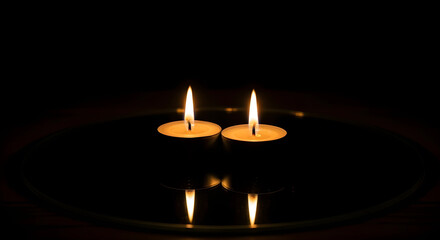 Two burning candles on dark background