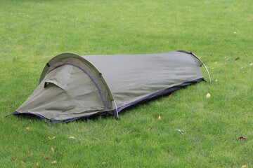 A durable, olive-green bivy tent stands ready on grass, perfect for a single person seeking a...