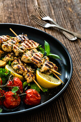 Greek style chicken skewers souvlaki with roasted potatoes and cherry tomatoes on wooden background	