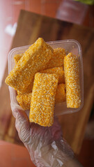 Jakarta, Indonesia 30 June 2025 : Hand holding a fried cheese roll with gooey cheese dripping....