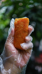 Jakarta, Indonesia 30 June 2025 : Hand holding a fried cheese roll with gooey cheese dripping....