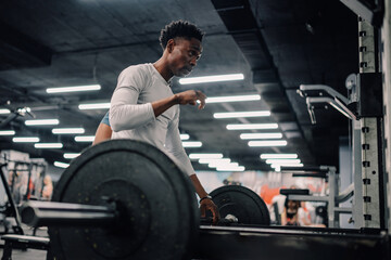 Determined athlete preparing weights for intense workout in modern gym