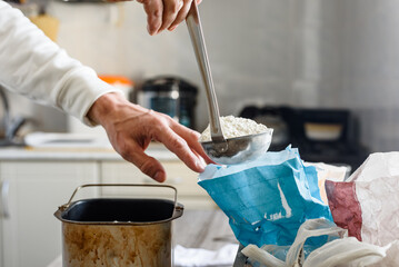 Closeup photo of male baker adding flour to raw dough while making bread. Preparing dough for bread...
