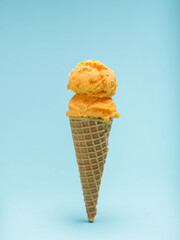 Double Scoop of Orange Ice Cream in a Waffle Cone Isolated on Blue Background.