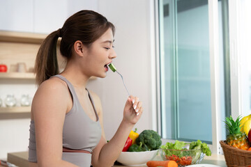 Wellness and Healthy Eating. Young woman enjoying a fresh vegetable snack in a bright kitchen.