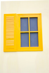 Bright Yellow Window Frame and Louvered Shutter Against a Cream-Colored Wall