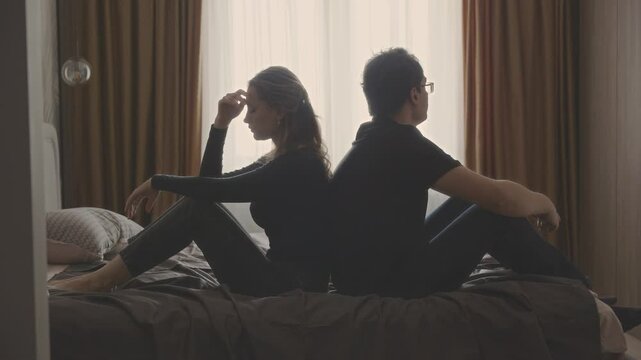 couple quarreling concept of family relationship problems divorce, man and woman cry sitting at bed resentment towards each other, in dark bedroom. guy cheated on girl. betrayal jealousy broken heart